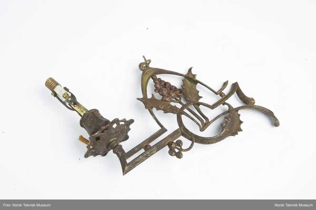 Lysekrone / hengelampe i metall for sju lys (seks lys + ett i midten). Lampa er ødelagt og i mange deler, oppheng, løse pæreholdere, glassbeholder, kuppel etc.