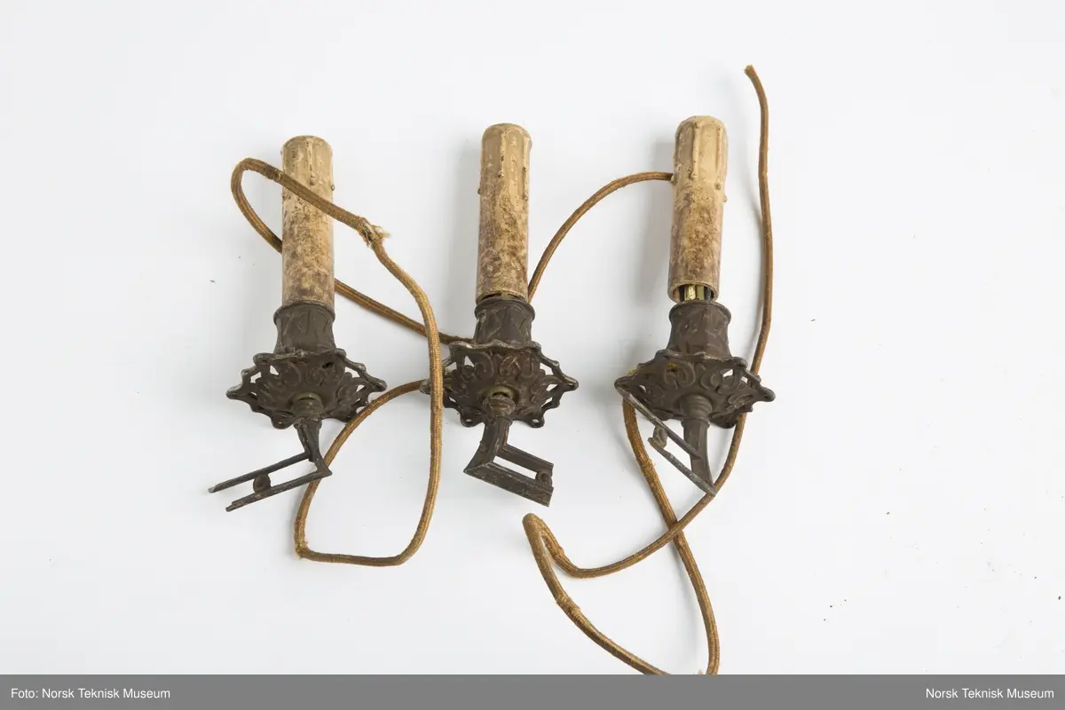 Lysekrone / hengelampe i metall for sju lys (seks lys + ett i midten). Lampa er ødelagt og i mange deler, oppheng, løse pæreholdere, glassbeholder, kuppel etc.