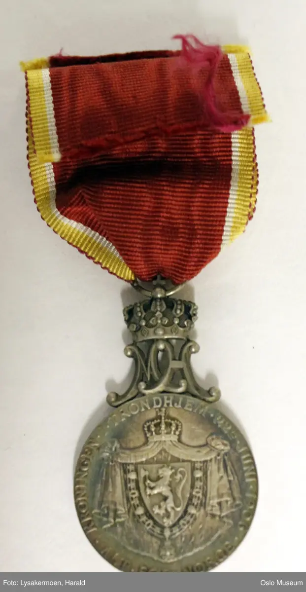 Rund medalje i bånd.

Medaljen er toppet av de sammenflettede bokstavene H og M, disse bærer en kongekrone. Båndet er festet til kronen med en sølvhempe. Båndet er rødt, kantet med hvitt, gull og rødt Medaljen er patinert - gir blåskimrende effekt.

Etuiet er av papp. Det er rødt med en gylden krone på lokket. Foret er hvitt, av silke og bomull. Forsølvet lukkemekanisme. Etuiets mål - L: 10,5 cm. B: 5,7 cm.
