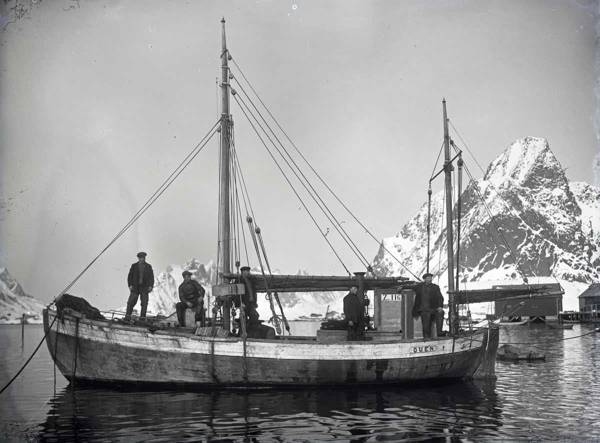 Fem mann på dekk med fjell i bakgrunnen - Fiskeskøyten 'Duen'.