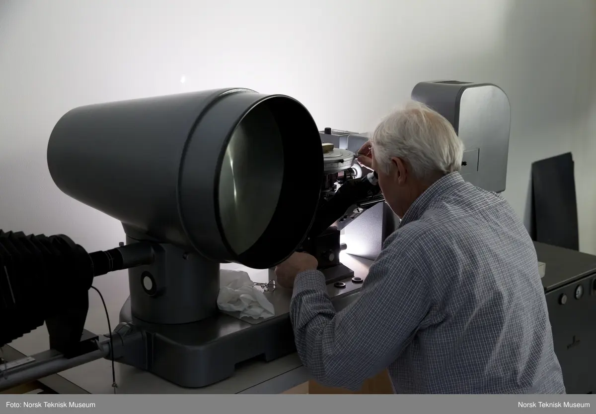 Mikroskopdelen av gjenstanden inkludert belguttrekk for fotografering (inkludert snorutløser), stang til å montere kamerabelg og to tekstilkapper til å legge over gjenstanden
ADVARSEL: Pæra som sitter inne i kabinettet (til høyre på bildet) er en overtrykkspære. Håndteres meget varsomt på grunn av risiko for eksplosjon. Bruk ansiktsskjerm om den håndteres.