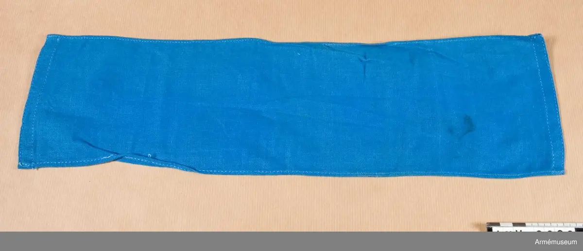 Armbindel av blått bomullstyg. Användes vid fälttjänstgöring och betecknar presstjänst.

Samhörande nr är 9605-9650 + 9659-9666.