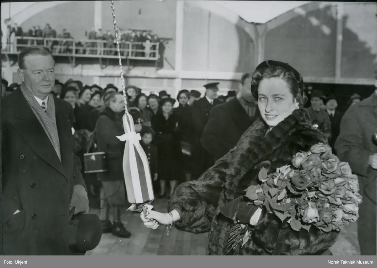 Direktør Aamundsen og prinsesse Ragnhild med champagneflasken før dåp og stabelavløpning av cargolineren M/S Sandanger, B/N 489 på Akers Mek. Verksted 3. mars 1951. Skipet ble levert i 1951 til Westfal-Larsen & Co.