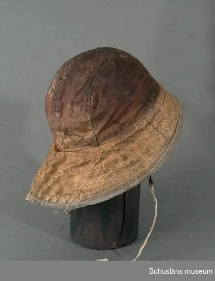 Huvudbonad vid bland annat fiske. Skyddar mot regn och vattenstänk.
Fodrad med rosafärgad bomullsflanell.
Isydd lapp anger storlek 60.

Ingår i redskapsbestånd ur sjöbod från Hällsö, Havstenssund, Tanum sn.
Se UM017521