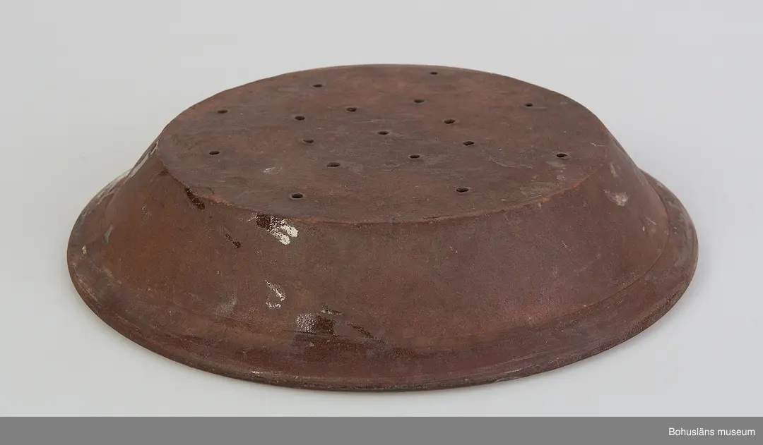 Fat med avrinningsfunktion; 17 hål om 5 mm diameter, radiellt placerade på botten. Gulglaserad insida. Uppåtböjd sida och utvikt bräm, oglaserad ut- och undersida.