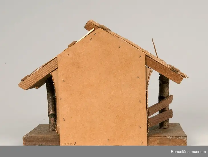 Stall med halmtak, trästolpar samt golv och vägg av masonite. Märkt UM19818:1
18 st figurer tillhör julkrubban. De är märkta UM19818:2.
Krubba, Jesusbarnet, Maria, Josef, en herde, de tre vise männen, en åsna, en oxe, tre liggande får, fem stående får varav ett betydligt större.
En av de tre vise männen märkt: Germany
Elastolin brukar denna typ av plastisk massa benämnas - egentligen ett  tyskt inregistrerat varumärke på en kompositmassa.