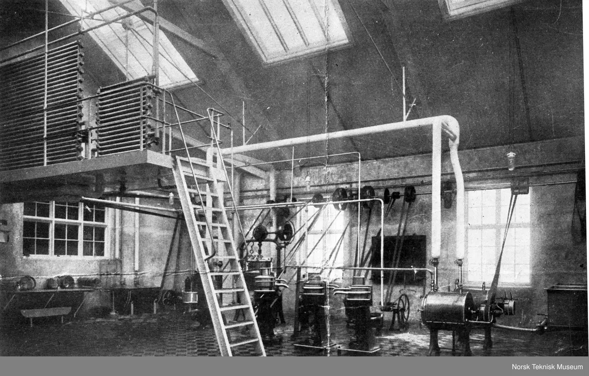 Fabrikkinteriør, med stige og remdrift. 