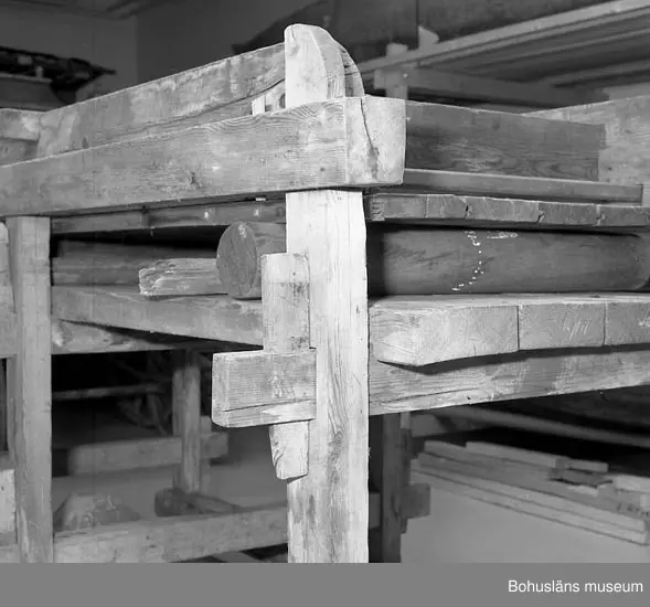 Trämangel med vagga för stenen. Två tjockare, två tunnare.
Beata Olsson  öppnade första lanthandeln i området vid Brattås, Morlanda (Henån) på 1880-talet i hus vid vägen. Mangeln uthyrdes samtidigt som lanthandeln drevs. Den var placerad i ett magasin bredvid och hyrdes av byns (Brattås) invånare. Under senare år användes den mest av
Beata Olssons släktingar. Nedmonterades något år innan den skänktes till museet.
Beata Olsson kom från Tegneby  socken. Givaren lanthandlare i Brattås.
Nuvarande affären flyttad snett över vägen längre ned i backen.