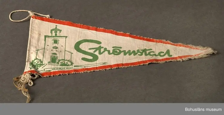 Trekantig vimpel. Naturfärgad bomull med textiltryck. Röd kant och i grönt bild av Strömstads kyrka och namnet "Strömstad".
Sammanhör med UM026180 - UM026184.
Användar- och förvärvsuppgifter se UM026180