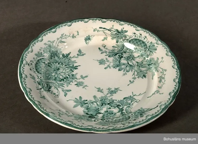 Tallrik modell "Anna". 
Stämplad med en stämpel som användes mellan åren 1902-1904. 
I priskurant från 1902 avbildas servisen med detta mönster, men omnämns endast som "tryckt dekor".
I priskurant från 1915 finns den med på färgplansch under namnet "Grön Anna".
Ägaren eller en man med anknytning till Göteborgs Porslinsfabrik lär ha kommit från Svarteborgs socken, Bohuslän. Han var god vän med fröken Anna Axelsson (1904-1985), Rom Östergården 1:12, Dingle, Svarteborg socken. Anna arbetade en stor del av sitt liv på Dingle mejeri. Efter henne lär servisen ha kallats "Anna". Uppgiften kommer från personer i Svarteborgs hembygdsförening i början av 1990-talet, vilka tidigare fått del av denna berättelse.
(Om ovanstående stämmer bör Anna ha varit nyfödd flicka när namnet på servisen bestämdes.)
År 1916 köpte Rörstrand Göteborgs Porslinsfabrik och flyttade 1923 all sin produktion dit. I köpet ingick även en rad modeller bl.a. denna servis som Rörstrand fortsatte produktionen av. Dekoren återupptogs på 1960-talet, men på servisgods av helt annan formgivning. Mönstrets namn ändrades då från "Anna" till "Grön Anna".
Mönstret har en ren nyrokokoformgivning. Det har i mindre omfattning även producerats i en lila färg. Mönstren "Anna" och "Grön Anna" har haft stora försäljningsframgångar och en av Göteborgs och Rörstrands långkörare.

Litteratur:
Göteborgs porslinsfabrik. Priskurant 1920.
Priskurant öfver Göteborgs porslinsfabriks tillverkningar 1920.
Artikel i Antik & Auktion nr 1 1983. Göteborgs porslinsfabrik - den okända fabriken där Grön Anna föddes. Skriven av Jane Fredlund.