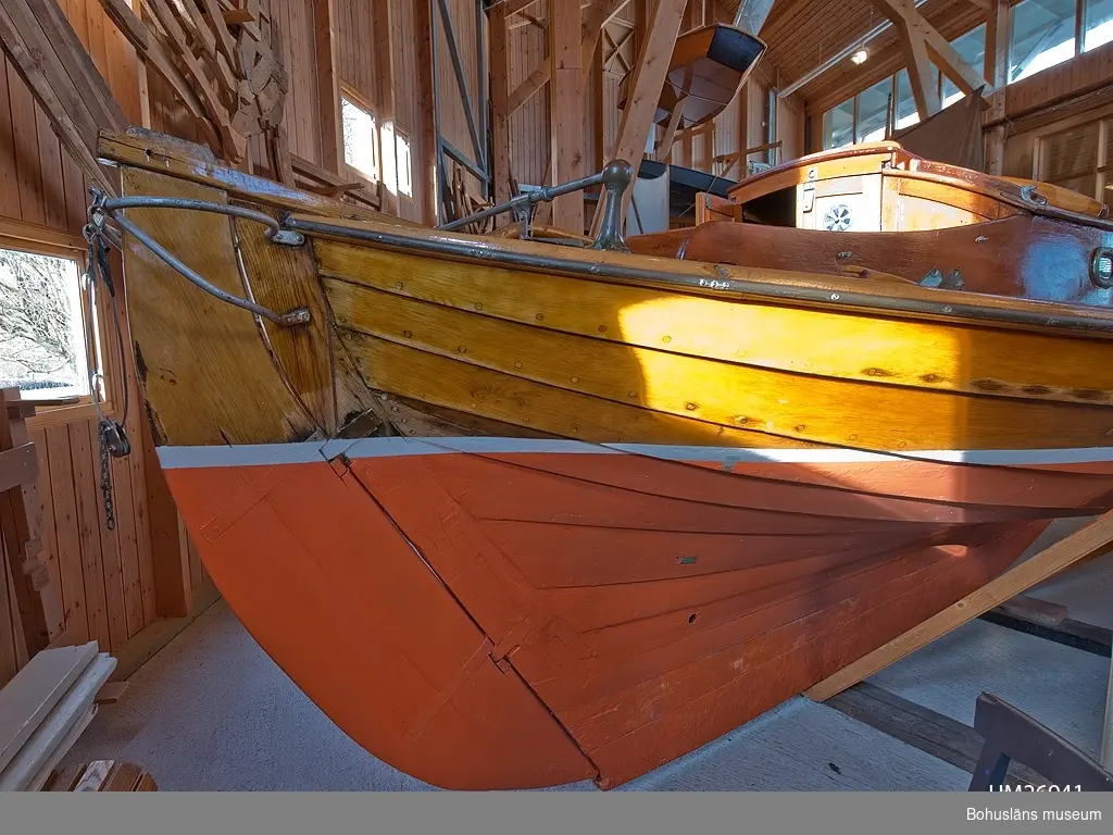 Spetsgattad. Klinkbyggd. Bord och spant av ek. Borden är nitade.
Däck av oregonpine. Ruff av mahogny och oregonepine (taket). Masten (H 10,3 m) och bommen (L 3,1 m) är gjorda av oregonpine.
Tidigare var båten gaffelriggad men i samband med en ombyggnad 1952 fick hon däck, ruff och en ny modern rigg samt kryssfock och storsegel av bomull tillverkat av Hasses segelmakeri i Göteborg, se UM026494 - UM026495. Se Länkade filer under Tilläggsinformation.
På sittbrunnens sarg sitter en namnskylt i trä; "NYMF".
Ett blått kapell, sprayhood, med två vita stänger från 1980-tal samt en båtshake förvaras i ruffen. Se Länkade filer under Tilläggsinformation.

Båten ägdes på 1930-talet av Karl Otto Jonasson. År 1941 sålde han den till Folke Gunnarsson och Rune Olsson. Fem år senare köpte Folke ut Rune.
Folke var med i Segelsällskapet FRAM i Göteborg. Båten kallades Nymf och hade nr 64 i segelsällskapet FRAM. År 1988 tog Karl-Erik Karlsson över båten.

Enligt Sveriges befolkning 1900 heter båtbyggaren Karl Alfred Fredriksson Stjërn, född i Kville 1857.
 
Litteratur: 
Börjesson, E, Börjesson, L., Dunér, m fl.: Kostern. Segelsällskapet Fram 100 år. 1896-1996. Göteborg 1996.
Sörenson, Reiners: Stjerns båtbyggeri på Galtö. Ur Träbiten nr. 93, Föreningen Allmogebåtar, Göteborg 1996.
Hasslöf, Olof: Svenska Västkustfiskarna, Stockholm 1949, sidan 296 ff,
Fredriksen, Christine: EBBA och NYMF - nöjesbåtar vid Bohuskusten. BOHUSLÄN. Årsbok 1999. Handel och hantverk. Bohusläns Hembygdsförbund och Bohusläns museum, s. 87-104.

Se Bilagepärmen UM26491: Träbiten nr 93 samt information från Segelsällskapet FRAM.
Gaffel och äldre bomullssegel finns el. uppgift från givaren kvar.
Uppgifterna kompletterade 2002-09-06/A-LS

Se Bildarkivet UMFA55001:1, familjebild från 1934 samt UM031358, prispokal från 1935.