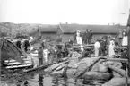 Bilden är tagen vid Skandinaviska Fiskerimötets i Marstrand besök på Mollösund 1904. Flera uppklädda personer stiger i land från småbåtar. Till vänster står en del av lokalbefolkningen och tittar nyfiket.