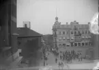 Kungstorget. Lysekil, med en procession med musik, hästskjutsar och ridande