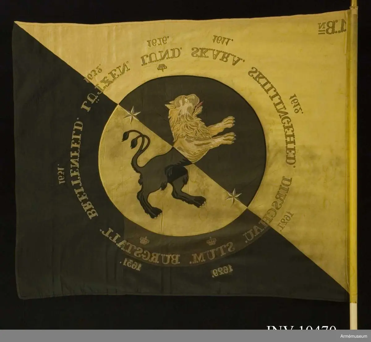 Duk av fansiden i fyrskaftad kypert, delad diagonalt i två fält - det inre gult och det yttra svart. I mitten en cirkel med 800 mm radie med omvända färger och där inne Västergötlands sköldemärke: ett lejon, gult på det svarta och svart på det gula fältet. I fältens delning finns två sex-uddiga stjärnor i guld. Lejonets svarta är applicerat fansiden  med kantsöm i svart silke, det gula är dels applicerat fansiden, dels schattérsöm i gult och vitt siden. Tungan fodrad i rött silke. Omkring vapnet, genombroderat i guld, finns segernamn: SKARA med "1611" under, SKILLINGEHED med 1612, DIRSCHAU och1627,  krönt STUM och 1629, krönt BURGSTALL och 1631, BREITENFELD och  1631, LÜTZEN och 1632 samt krönt LUND med 1676. I övre inre hörnet finns "1.Bn" broderat i guld (två streck  under N). Duken är kantad med ripsband, svart på det svarta och gult på  det gula. Fastspikad med förgyllda spikar. Kravatt av gult och svart kypertvävt fansiden. Guldfrans på kortändarna.

Hel längd 2860 mm, frans 10 mm, bredd 260 mm. Stång av furu - vitmålad. Doppsko konisk med rund knopp av förgylld mässing. Längd 2560 mm. Spets av förgylld mässing, ursprungligen med Oscar I:s krönta monogram som senare felaktigt byttes mot Gustav V:s krönta spegelmonogram inom lyra av lager. Längd 330 mm. Fodral av mörkblått (svart) kläde med skinnskodd topp, dragsko och ficka för spetsblad. Längd 1820 mm, bredd 180 mm.