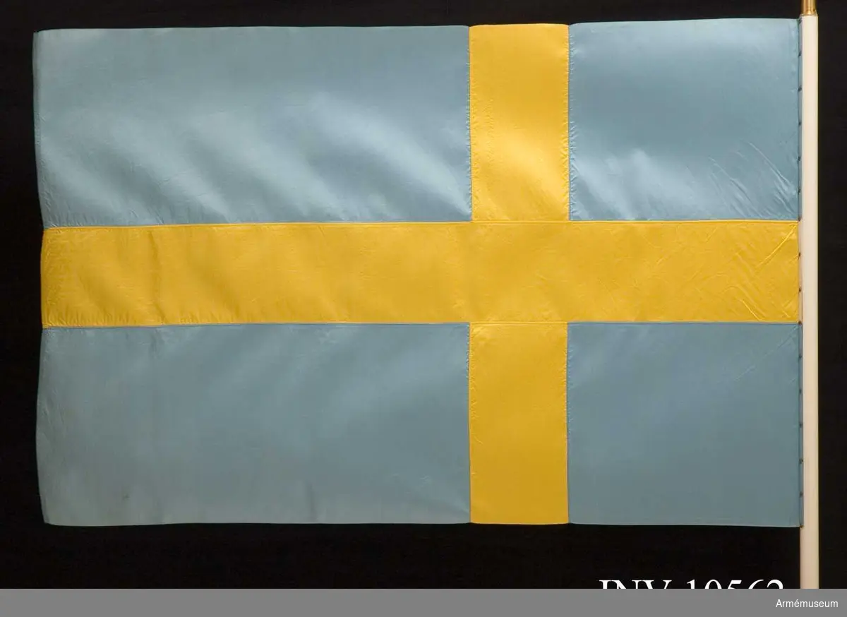 Grupp B I.

Duk av blått och gult siden, s k korsflagga. Fodral av blått kläde är märkt på den undre fickan: "Int 2". Fickan innehåller spetsen med Gustav V:s namnchiffer.