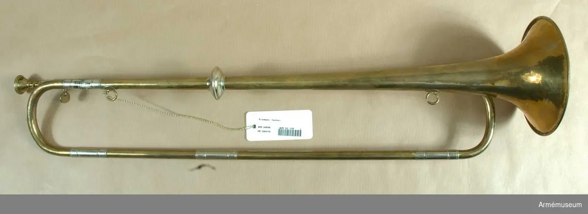 Trumpet av mässing och vitmetall med en vindling. Höjd utan munstycke 69 cm, med d:o 72 cm, diameter 15 cm. Trumpeten är signerad på klockstycket: Bohland & Fuchs, Graslitz. Texten är dock nästan bortputsad.