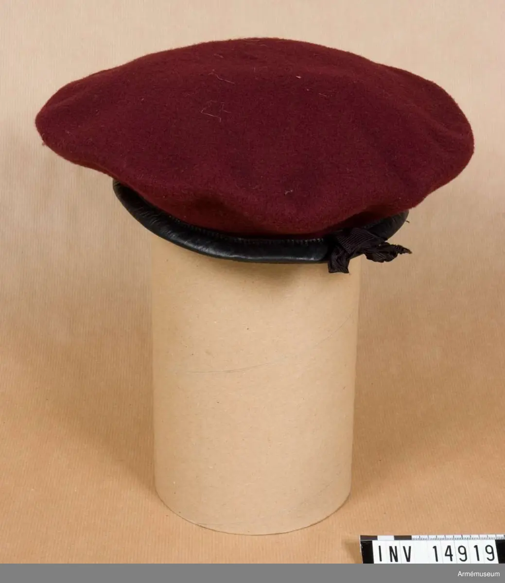 Grupp C I.
Rund basker av rödbrunt kläde med svart läderkant. Inuti ett svart silkesband varmed baskern förstoras eller förminskas. Foder av svart bomullstyg m påskrift "7", "Kangol Wear Limited" (= Kangol Klädes AB), "1942". På baskerns ena sida två lufthål.
Gåvan förmedlad av major de Salis, engelsk biträdande militärassistent.

LITT  Taschenbuch. Britisches Heer. 1944. Felduniformen des britischen Heeres. Bild 1. "Baskenmütze" för fallskärmsjägare, i brun färg. Enl kapten W Granberg.