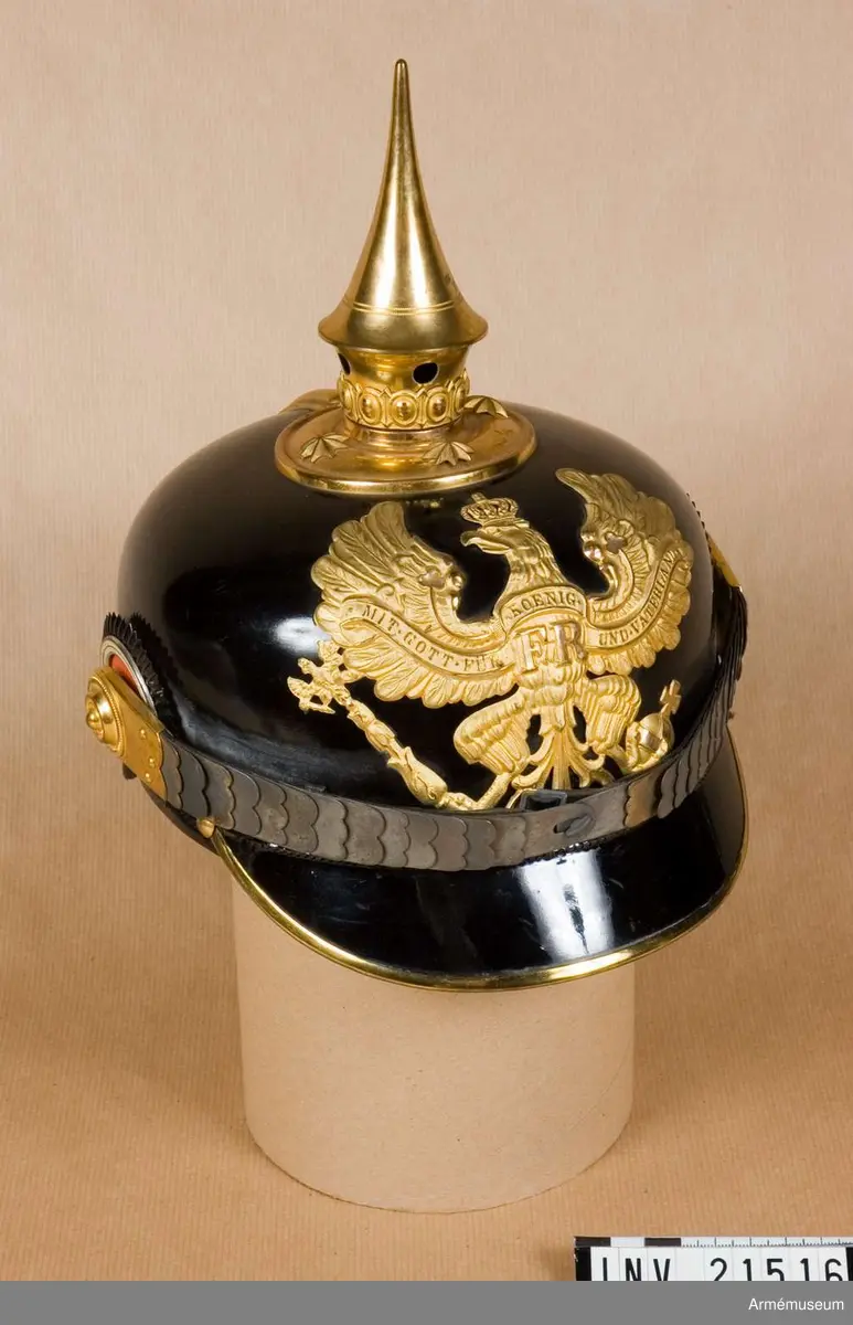 Hjälm av lackerat svart läder med fram- och bakskärmar. På baksidan finns en skena som går från spetsen till nacken. Alla metalldelar är av mässing.

Foder av svart läder och grönt siden. Hakremmar av läder med flata fjäll. Kokarden på höger sida under hakremsrosetten är rund och svart-vit-röd (tyska statens färger); kokarden på vänster sida är rund och svart-vit (Preussens färger).