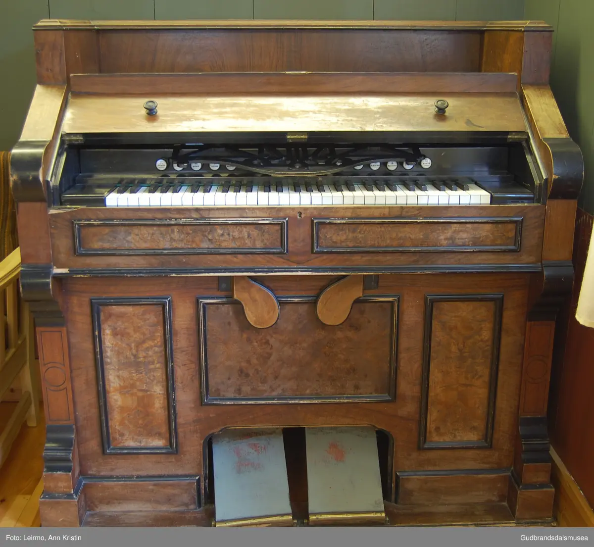 Orgel, brukt i Lesja Kyrkje. Rektangulært med pumpe-pedaler. Lokk over piano-brett er skåret. Høy rygg og vegger bak med profilert list oppå. Har en lysestake i messing på ene siden, den andre mangler. Delt inn i kvadrater og rektangler med lister, eller intartsia-arbeid. Håndtak i messing. 
