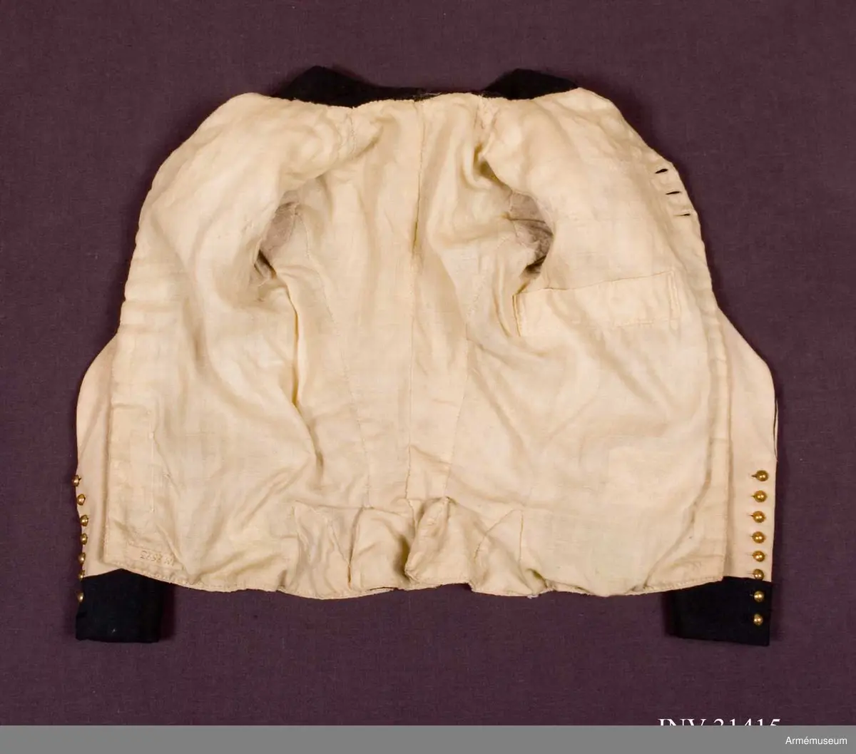 Jacka m/1792, av vitt kläde med hög krage, passpoaler, ärmuppslag och andra detaljer i mörkblått kläde.
Plagget är kraftigt svängt mitt fram, knäppt med tre knapprader med 18 guldfärgade klotknappar i varje rad, varav bara de 3 på mitten går att knäppa. Övriga knapphål är stumma.
Vid axeln finns stoppade axelkarmar av vitt kläde med slitsar fodrade med blått kläde. Här finns även fastsydda axelklaffar av enkelt vitt kläde med en blå stjärna applicerad. Axelklaffarna fästs ner med en enkel klotknapp av samma typ som övriga.
Ärmarna är tvåsömsärmar med blå passpoaler i båda sömmarna och sprund längst ner på ärmen som knäpps med 8 mindre kulknappar i varje. I höger ärm saknas en knapp längst ner.
Två grunda horisontella fickor. Litet skört bak.
Jackan är fodrad med fint kypertvävt ylletyg i bålen, men med tuskaftvävt linne- eller hampatyg i ärmarna.