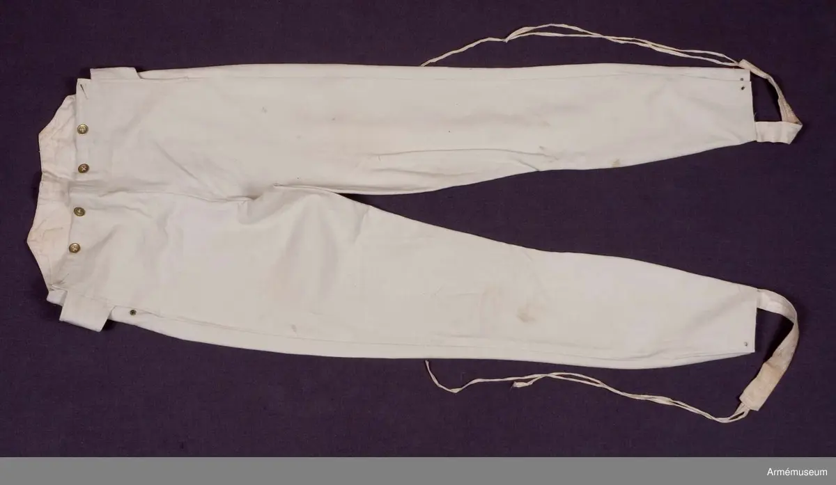 Vita smala byxor eller pantalonger.

Byxorna är sydda av vitt kläde med lucka fram. De är konstruerade med två fram- och två bakstycken, samt ett infällt stycke med oklar funktion upptill på baken. Hel lucka som knäpps i varje sida med en knapp samt en (möjligen sekundär) tryckknapp av mässing. Hög linning bak. Byxbenen är formade över vaderna och avsmalnande nertill. 
Byxorna är ofodrade, men luckan, linningen bak, samt slitsarna nertill i benen har en infodring av vitt linne. Spänntamp i varje sida av luckan som kan knäppas i ryggen bak. I midjan fram sitter ytterligare fyra knappar för hängslen, samt två bak. Samtliga knappar är av mässing förutom knappen i spänntampen som är av tjock pärlemor.
Nertill på benen finns en slits i varje bens utsida med sydda snörhål. Mot dessa snörhål ska det knytas fast två remmar som sitter i en hälla av vitt linne att knyta under fötterna.