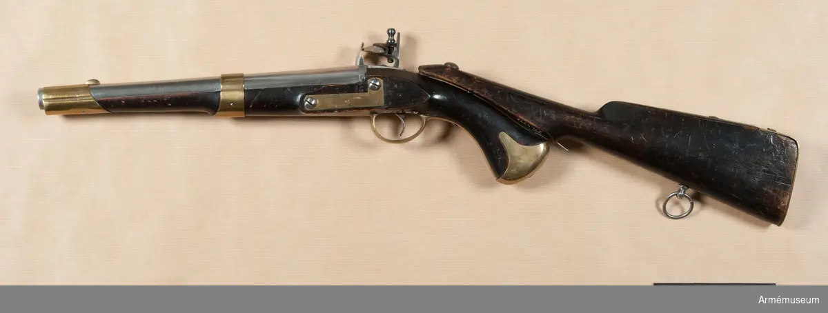 Pistol med flintlås.
Studsarpistol m/1807 (1806?) av Helvigs konstruktion. Längd med påsatt löskolv: 712 mm. Pipan är rund. Svansskruven har baktill en hake, som är inpassad i ett hål i det vid stocken fästa svansjärnet. Ett högt, båtformigt mässingskorn sitter 4,2 cm bakom mynningen. På svansjärnet sitter ett högt ståndsikte. Svansjärnet fasthålls av en uppifrån isatt korsskruv. På pipans översida krönt N T (Norrtälje), på undersidan ett P och på vänstra platten en otydlig stämpel. På svansjärnet en otydlig kronstämpel. Loppet har 4 spiralräfflor.

Låset har platt bleck, fängpannearm och eldskärm. Studeln har en egendomlig, kantig form. Slag och eldstålsfjädrarna är så krökta att främre låsskruven går inom deras bukter. pannskruven går inifrån, men skruven för eldstålsfjädern utifrån. På bleckets utsida under eldstålsfjädern ett S, på insidan siffran 2 och en otydlig kronstämpel.

Stocken är av björk och svart, till vänster om varbygeln främre arm en otydlig stockmakarestämpel och till höger om denna arm spår av rött lacksigill. Ovanför sidblecket är inslaget numret 16. Beslagen är av mässing. Kolvkappan har rätt korta, avrundade flikar och är hoptryckt från sidorna. Den fasthålls av en skruv i centrum. Varbygelns bakre arm går ned till kolvkappan och är fäst med en skruv. Den korta främre varbygelsarmen har docka. Sidblecket är platt och böjt i rät vinkel. Pipan fasthålls av två band, vilka kvarhålls av stift. Näsbandet är upptill utskuret för kornet och har nedtill en kort, bakåtgående spets. Det andra bandet har nedtill en kort framåtriktad spets. På sidblecket, näsbandet och kolvkappan inslaget G S. På varbygelns bakre arm en stämpel med ett monogram av A.L.

I kolvens övre sida är ett kraftigt "anslagsjärn" infällt och till ungefär 1 cm från svansjärnets bakände. fasthålls av fyra skruvar. Anslagsjärnet går från kolvkappan till ungefär 1 cm från svansjärnets bakände. Längst ned vid kappan finns i järnet ett runt hål och omkring 8 cm längre upp har det ett avlångt hål.

Löskolven är svart, av björk och har bakplåt av mässing. Löskolvens "hals" är avsneddad på undersidan så att den där noga passar till pistolkolves översída. I detta avsneddade parti är "häftjärnet" infällt och fasthålls av tre skruvar. En bit nedanför häftjärnets överkant sitter "häfttappen". Denna består närmast häftjärnet av en omkring 6 mm hög, cylindrisk tapp med 7 mm diameter. På denna tapp sitter ett rektangulärt, 13 mm långt, 5 mm brett och 5 mm högt ax på tvären med häftjärnet längdriktning. På insidan av häftjärnets är en lång "häftfjäder" placerad. Häftfjädern sticker nedtill ut omkfing 1,7 cm nedanför häftjärnets bakände. Litet ovanför denna bakände genombryts häftjärnet av ett hål, genom vilket en på häftfjädern sittande tapp utsticker.

När man påsätter löskolven, inpassar man häfttappen i anslagsjärnets övre hål, vrider löskolven åt vänster och trycker in häftfjäderns utstående del. Då anslagsjärnet och häftjärnet ligger på varandra, släpper man häftfjädern, varvid häftfjäderns tapp drivs ned i anslagsjärnets runda hål samt sålunda fastlåser löskolven vid pistolen. Därigenom kunde man skjuta med pistolen stödd mot axeln alldeles som med ett gevär. Ett par pistoler av denna modell består av en studsarepistol, lika den som ovan beskrivits, och en slätborrad blänkare- eller flankörpistol (se AM 4780). Till varje pistolpar hördes en löskolv, också kallad "löst anslag", och en lös laddstock. Löskolven och laddstocken passade till bägge pistolerna.