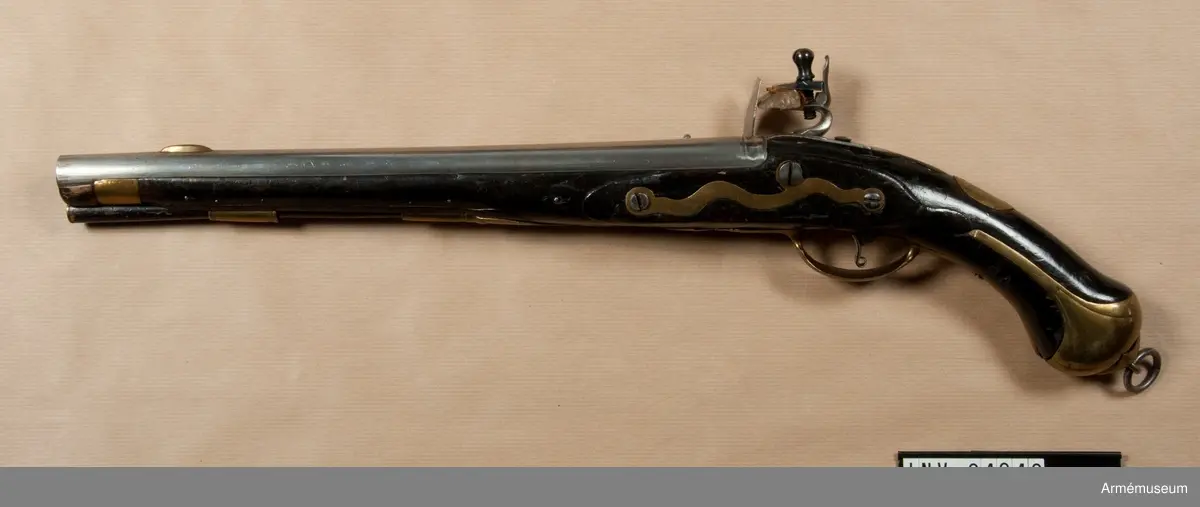 Pistol med flintlås.
Beslag av mässing. Laddstock av trä med mässingsbeslag. På kammarstycket ett krönt F samt bokstaven Ö. På kolvhalsen en mässingsmedaljong med Gustaf III:s krönta namnschiffer. På kolvhalsens H sida nummer 25 inskuret och på dess motsvarande bokstäverna V B. Vid kolvknappen en ring av järn fästad, pistolen tycks vara par med AM 1932:4769.