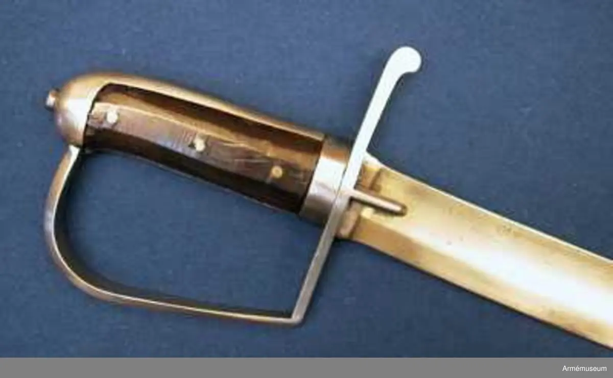 Klingbredd upptill: 36 mm. Klingan är krökt samt på större delen av sin längd eneggad och skålslipad. Udden sitter nära nog i klingans mittlinje. På en längd av omkr 31 cm från udden har klingan egg även på rygg-sidan. Upptill på yttersidan står "ZETTERBERG" och upptill på innersidan är en stämpel med bokstäverna C. F. K. inslagen.

Fästet är av järn. Tången är bred, och vid den är på var sida en skena av mörkt trä anbringad, vilka båda skenor fasthållas av tre genomgående nitar. Nederst omgives kaveln av ett ringliknande, 1,1 cm järnbeslag. Baktill har kaveln ryggbeslag, som uppåt övergår i en låg avrundad kappa. Tångens översta del fasthålles av en påskruvad, åttkantig liten mutter, som sitter ovanpå kappan.
Parerstången är rak och har fyrsidigt tvärsnitt. Baktill avslutas den av en nedböjd knapp. Upptill på parerstångens bakre arm är siffran 8 inslagen. Ett par små styrskenor, som har avfasade kanter och avrundade ändar, utgår från undersidan av parerstångens mitt.Från parerstångens främre ände utgår hanbygeln i tvär vinkel men går ej rakt uppåt utan snett framåt. Den har på framsidan snedfasade kanter. Handbygelns övre ände är instucken under kappans främre kant.