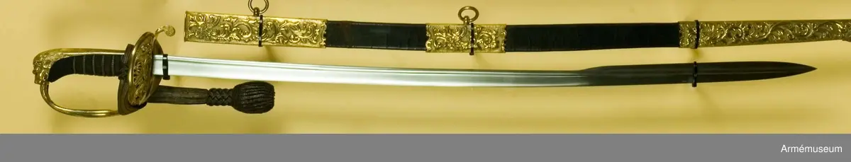 Sabeln påminner om m/1859. På parerplåten finns Karl XV:s krönta namnchiffer.
