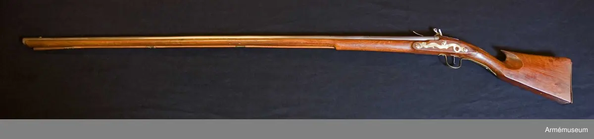 Grupp E XIV.
Loppets relativa längd är 75,8 kal.Afrikanskt gevär med flintlås. Pipan är längre och kolvens form  är annorlunda än på AM.049655-9. Barker. På kolven högra sida återfinns numren 26 och 166.