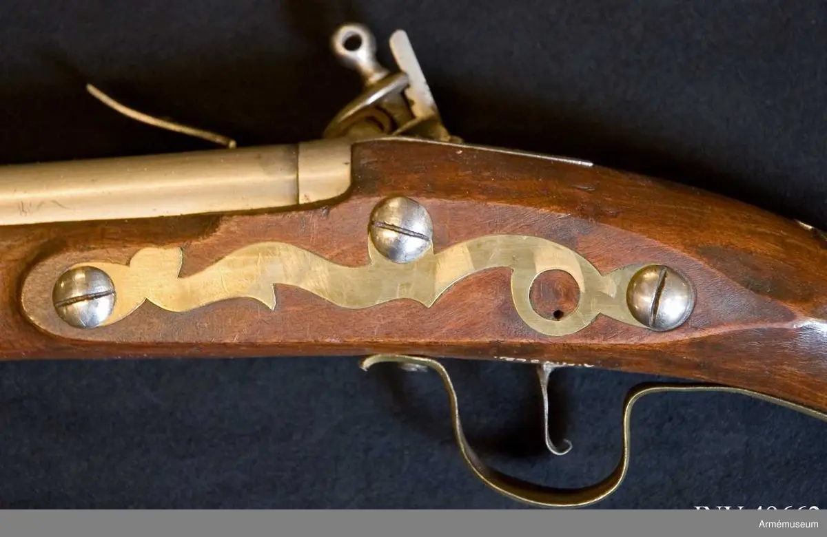 Grupp E XIV.
Loppets relativa längd är 75,8 kal.Afrikanskt gevär med flintlås. Pipan är längre och kolvens form  är annorlunda än på AM.049655-9. Barker. På kolven högra sida återfinns numren 26 och 166.