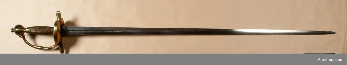 Klingan är tveeggad med flata åsar. På bägge sidor finns upptill en omkring 193 mm lång blodrand. Nedanför blodrandens slut finns på klingan en pilspetsliknande stämpel. 

Fästet är av mässing och av drabanttyp. Knappen har närmast formen av ett vid polerna tillplattat klot, dock med skarp rygg på fram och baksidan. Diametern i sidled är 37 mm, men över ryggarna 40 mm. Höjden är 31 mm. Nitknappens diameter är 16,5 mm, dess höjd 10 mm. Den är instrypt på mitten och har en spetsoval, 20 mm lång fot. Halsen är instrypt på mitten och upptill spetsoval samt 13,5 mm lång. En rand eller snarare avsats markerar gränsen mellan knappen och nitknappen samt mellan knappen och halsen, en dylik går även runt halsens nedre del.
Kaveln har fram och bak en flat kant, men sidorna är avrundade. Den har upp och nedtill ett 9 mm brett beslag av tunt mässingsbleck, vilket är prytt med två ränder. I övrigt är kaveln lindad med två mässingstrådar, en smalare och en tjockare, båda hopsnodda av två parter, den ena höger-, den andra vänstersnodd. Lindningen har Iossnat.
Parerstången är rak och har spetsovalt tvärsnitt. Ändarna är avrundade och parerstången vidgas mot dessa. Avståndet mellan främre eggen och parerstångens framända är 68 mm, men från den bakre eggen till stångens bakända 55 mm. Den största tjockleken är för den främre armen 10 mm, men för den bakre 8,5 mm. Den största bredden är för bägge armarna 16 mm. Avståndet mellan klingans mitt och parerplåtens ytterkant är 45 mm, men mellan klingans mitt och innerkanten 40 mm.
