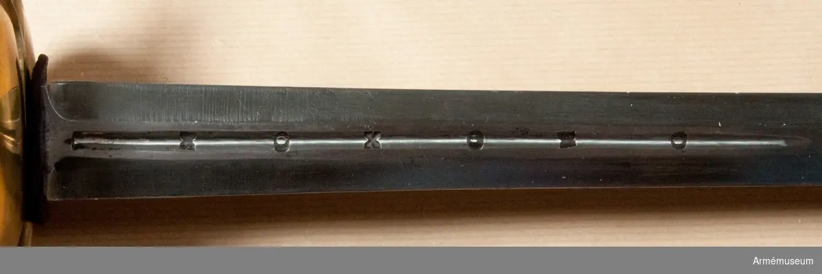 Klingan är tveeggad med flata åsar. På bägge sidor finns upptill en omkring 193 mm lång blodrand. Nedanför blodrandens slut finns på klingan en pilspetsliknande stämpel. 

Fästet är av mässing och av drabanttyp. Knappen har närmast formen av ett vid polerna tillplattat klot, dock med skarp rygg på fram och baksidan. Diametern i sidled är 37 mm, men över ryggarna 40 mm. Höjden är 31 mm. Nitknappens diameter är 16,5 mm, dess höjd 10 mm. Den är instrypt på mitten och har en spetsoval, 20 mm lång fot. Halsen är instrypt på mitten och upptill spetsoval samt 13,5 mm lång. En rand eller snarare avsats markerar gränsen mellan knappen och nitknappen samt mellan knappen och halsen, en dylik går även runt halsens nedre del.
Kaveln har fram och bak en flat kant, men sidorna är avrundade. Den har upp och nedtill ett 9 mm brett beslag av tunt mässingsbleck, vilket är prytt med två ränder. I övrigt är kaveln lindad med två mässingstrådar, en smalare och en tjockare, båda hopsnodda av två parter, den ena höger-, den andra vänstersnodd. Lindningen har Iossnat.
Parerstången är rak och har spetsovalt tvärsnitt. Ändarna är avrundade och parerstången vidgas mot dessa. Avståndet mellan främre eggen och parerstångens framända är 68 mm, men från den bakre eggen till stångens bakända 55 mm. Den största tjockleken är för den främre armen 10 mm, men för den bakre 8,5 mm. Den största bredden är för bägge armarna 16 mm. Avståndet mellan klingans mitt och parerplåtens ytterkant är 45 mm, men mellan klingans mitt och innerkanten 40 mm.