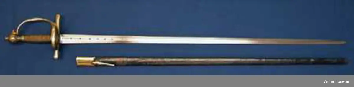 Klingan är tveeggad med flata åsar. På bägge sidor finns upptill en omkring 193 mm lång blodrand. Nedanför blodrandens slut finns på klingan en pilspetsliknande stämpel. 

Fästet är av mässing och av drabanttyp. Knappen har närmast formen av ett vid polerna tillplattat klot, dock med skarp rygg på fram och baksidan. Diametern i sidled är 37 mm, men över ryggarna 40 mm. Höjden är 31 mm. Nitknappens diameter är 16,5 mm, dess höjd 10 mm. Den är instrypt på mitten och har en spetsoval, 20 mm lång fot. Halsen är instrypt på mitten och upptill spetsoval samt 13,5 mm lång. En rand eller snarare avsats markerar gränsen mellan knappen och nitknappen samt mellan knappen och halsen, en dylik går även runt halsens nedre del.
Kaveln har fram och bak en flat kant, men sidorna är avrundade. Den har upp och nedtill ett 9 mm brett beslag av tunt mässingsbleck, vilket är prytt med två ränder. I övrigt är kaveln lindad med två mässingstrådar, en smalare och en tjockare, båda hopsnodda av två parter, den ena höger-, den andra vänstersnodd. Lindningen har Iossnat.
Parerstången är rak och har spetsovalt tvärsnitt. Ändarna är avrundade och parerstången vidgas mot dessa. Avståndet mellan främre eggen och parerstångens framända är 68 mm, men från den bakre eggen till stångens bakända 55 mm. Den största tjockleken är för den främre armen 10 mm, men för den bakre 8,5 mm. Den största bredden är för bägge armarna 16 mm. Avståndet mellan klingans mitt och parerplåtens ytterkant är 45 mm, men mellan klingans mitt och innerkanten 40 mm.