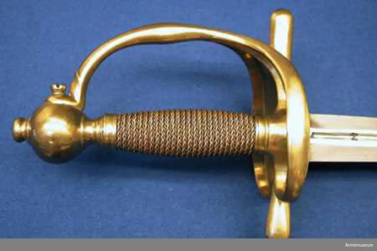 Klingan är tveeggad med flata åsar. På bägge sidor finns upptill en omkring 193 mm lång blodrand. Nedanför blodrandens slut finns på klingan en pilspetsliknande stämpel. 

Fästet är av mässing och av drabanttyp. Knappen har närmast formen av ett vid polerna tillplattat klot, dock med skarp rygg på fram och baksidan. Diametern i sidled är 37 mm, men över ryggarna 40 mm. Höjden är 31 mm. Nitknappens diameter är 16,5 mm, dess höjd 10 mm. Den är instrypt på mitten och har en spetsoval, 20 mm lång fot. Halsen är instrypt på mitten och upptill spetsoval samt 13,5 mm lång. En rand eller snarare avsats markerar gränsen mellan knappen och nitknappen samt mellan knappen och halsen, en dylik går även runt halsens nedre del.
Kaveln har fram och bak en flat kant, men sidorna är avrundade. Den har upp och nedtill ett 9 mm brett beslag av tunt mässingsbleck, vilket är prytt med två ränder. I övrigt är kaveln lindad med två mässingstrådar, en smalare och en tjockare, båda hopsnodda av två parter, den ena höger-, den andra vänstersnodd. Lindningen har Iossnat.
Parerstången är rak och har spetsovalt tvärsnitt. Ändarna är avrundade och parerstången vidgas mot dessa. Avståndet mellan främre eggen och parerstångens framända är 68 mm, men från den bakre eggen till stångens bakända 55 mm. Den största tjockleken är för den främre armen 10 mm, men för den bakre 8,5 mm. Den största bredden är för bägge armarna 16 mm. Avståndet mellan klingans mitt och parerplåtens ytterkant är 45 mm, men mellan klingans mitt och innerkanten 40 mm.