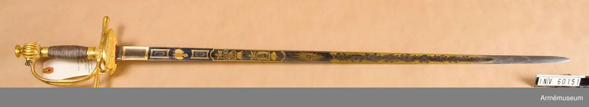 Grupp D II.
Fästet är av kommendertyp  med rak eneggad klinga, som är rikt dekorerad på bägge sidor med bl a Carl XIV Johans och kronprins Oscars namnchiffer.