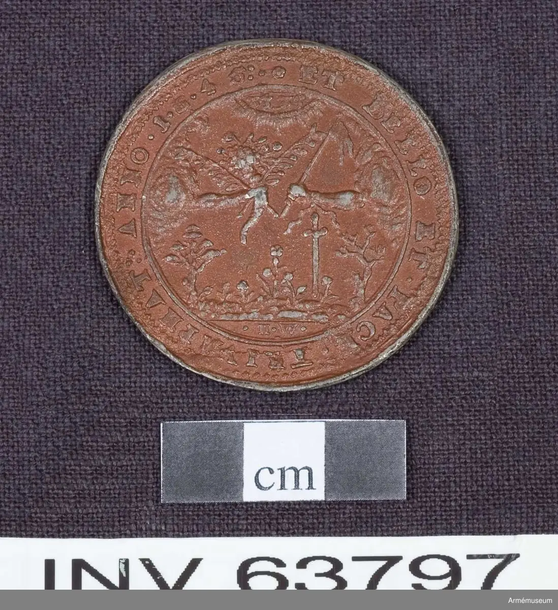 Medalj av 13. storleken. Freden vid Brömsebro den 13 augusti 1645. Medaljen är av brungjort tenn. Kring kanten på båda sidor en fin ornamentsrand.

ÅTSIDAN: "*.:CHRISTINA D:G:SVE:GOT:VAN:Q:REGINA & PRINC: HAE:M: D: F:.*" Bröstbild, nästan framvänd, i prydlig dräkt med stålkrona på nacken. Om halsen ett enkelt pärlband, på bröstet ett smycke. Omgiven av två med lager omlindade palmkvistar, upptill samman- hållna av en lagerkrans.

FRÅNSIDAN: "*ET BELLO ET.PACE.TRIVMPHAT:.ANNO 1.6.4.5:." Två händer sträcks fram från skyar ur motsatta sidor. Den ena handen håller ett ymnighetshorn fullt av blommor och frukter ochh två olivkvistar. Den andra håller en stång med en kluven flagga och har vid armleden ett svärd fastbundet. På marken träd och örter. Överst tecken (hebreiska? Se bilaga.) inom en strålande båge. I avskärningen "H.W."