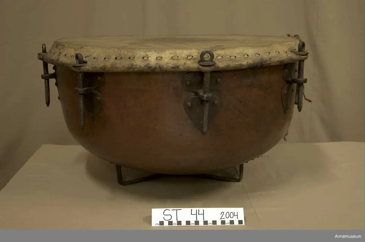 Grupp A.

Tillstånd 2005

Kittel:
Stor, vacker, orange och blank. Två prydliga lagningar där fot fäster i kittel.

Fot: 
Tredelad, stadig. Kan stå.

Spännskinn:
Ljust, fjälligt på mitten. Mycket. litet färgstänk. Efter spännringen fann jag två små trasigheter, annars intet.

Spännring:
Rostig. 

Spännskruv: 
Åtta stycken. Ett rep fastbundet i en av skruvarna.

Skruvfästen:
Åtta stycken. 

Bärrem:
Saknas.