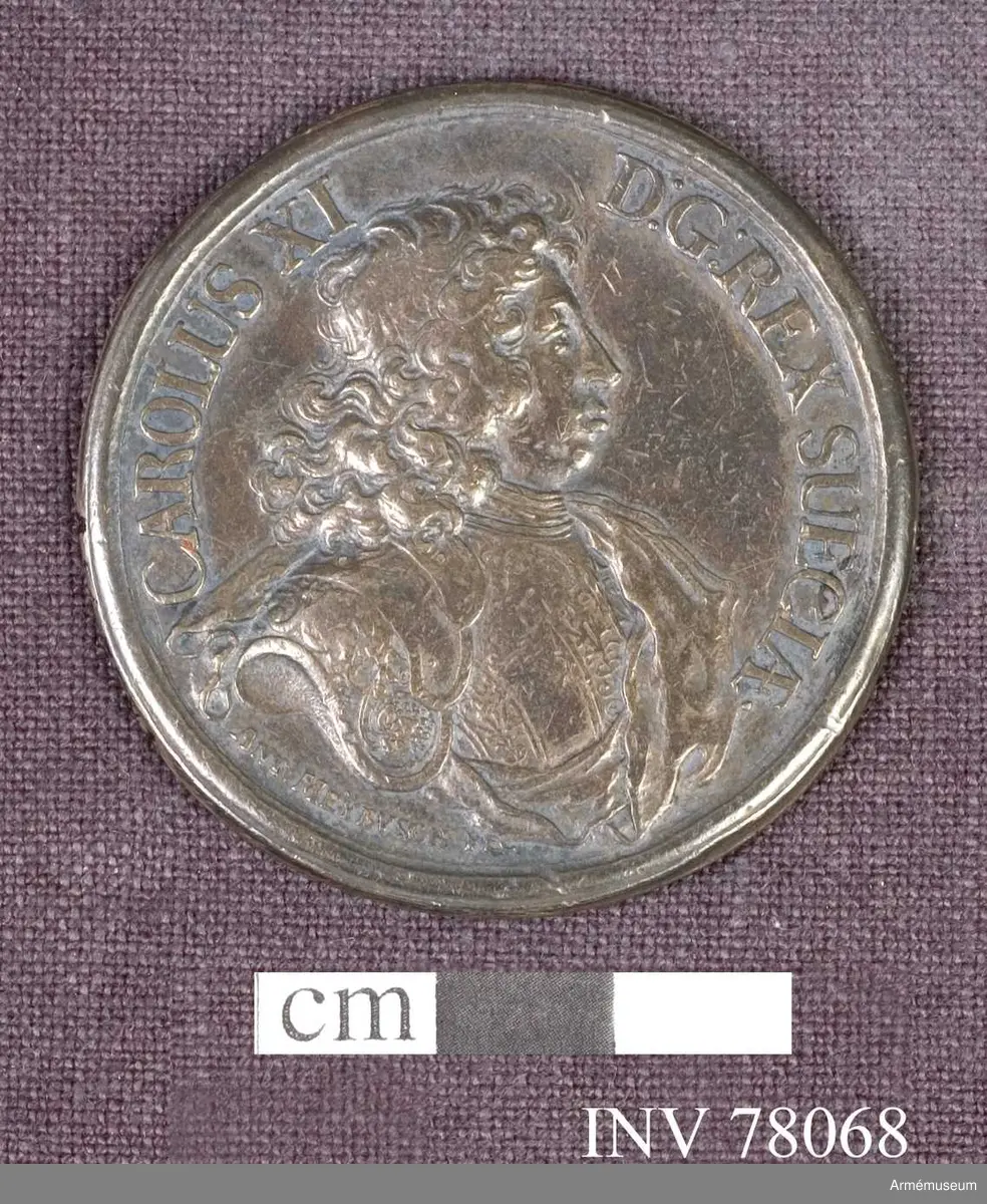 Grupp: M.
Åtsidan: CAROLVS XI. D: G: REX SUECIÆ. Bröstbilden åt höger i praktfullt harnesk samt snett över bröstet och venstra axeln mantelveck, som sluta bakom ryggen - Nedanför: ANT: MEYBVSCH FEC.

Frånsidan: AUSPICIIS DUCTUQUE SUO TER VICTOR IN ANNO. Tre lagerkransar. I avskärningen: ANNO 1676 D: 17. AUG: ET 4 DEC: A 1677. DIE 14 IULII.
