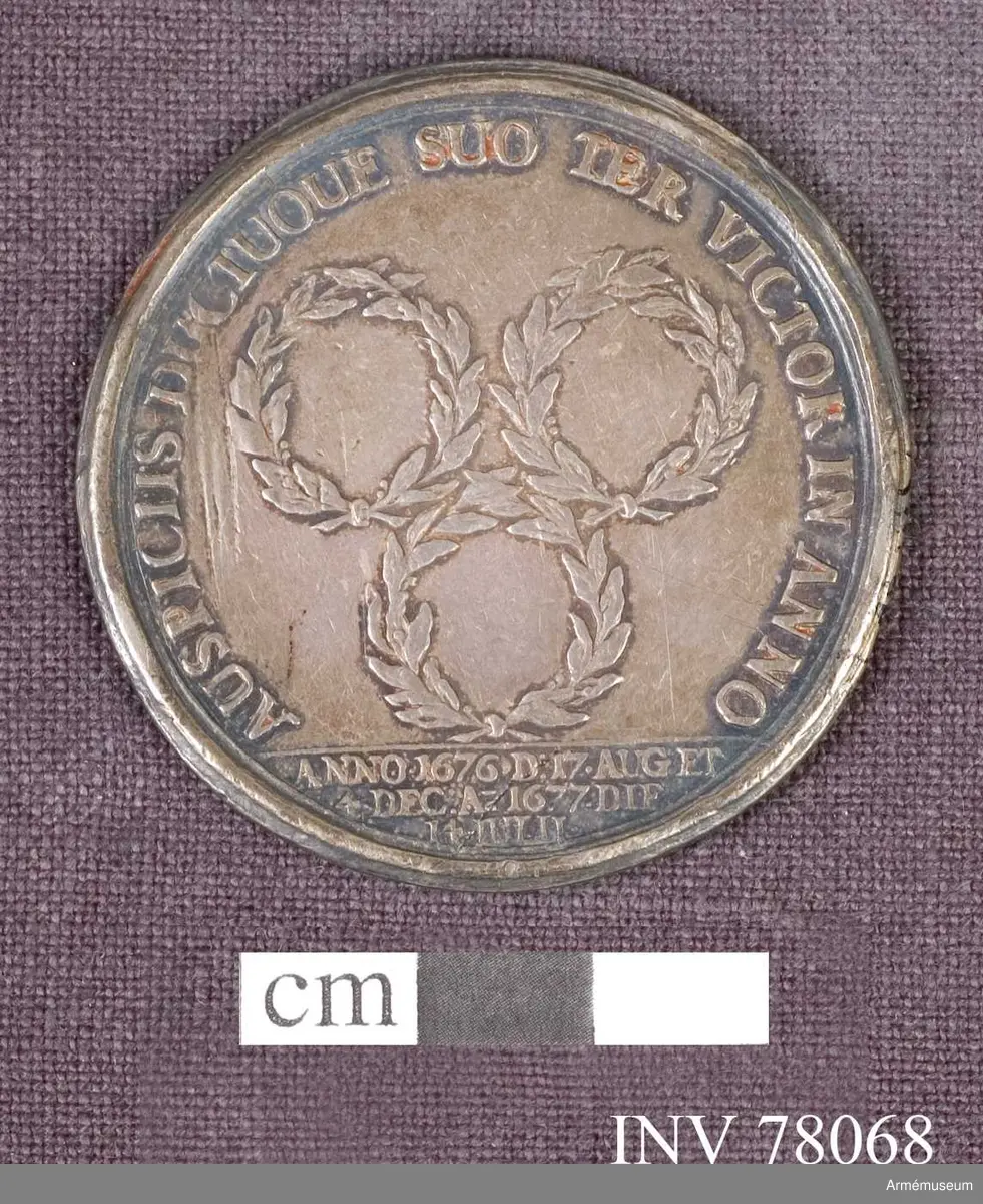 Grupp: M.
Åtsidan: CAROLVS XI. D: G: REX SUECIÆ. Bröstbilden åt höger i praktfullt harnesk samt snett över bröstet och venstra axeln mantelveck, som sluta bakom ryggen - Nedanför: ANT: MEYBVSCH FEC.

Frånsidan: AUSPICIIS DUCTUQUE SUO TER VICTOR IN ANNO. Tre lagerkransar. I avskärningen: ANNO 1676 D: 17. AUG: ET 4 DEC: A 1677. DIE 14 IULII.