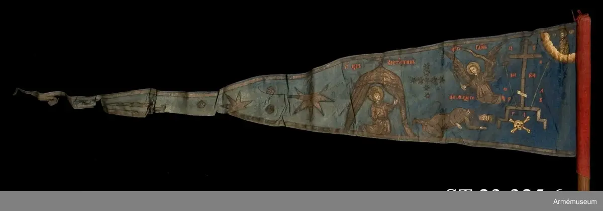 Duk av blå kinesisk sidendamast med målad dekor. Motivet föreställer den romerske kejsaren Konstantins vision av ett kors i skyn kvällen innan slaget vid Pons Mulvius år 312 e Kr mot Maxentius. En ärkeängel med svärd i handen (Gabriel?) svävar över den halshuggne Maxentius. Denna händelse ses som förklaring till att kristna kors började användas på militära fanor. Närmast stångsidan är också ett Golgatakors avbildat. Över detta syns ett moln där Kristus är avbildad. 
Strumpa av rött linne.