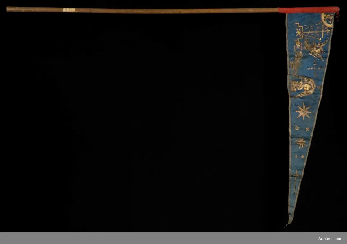 Duk av blå kinesisk sidendamast med målad dekor. Motivet föreställer den romerske kejsaren Konstantins vision av ett kors i skyn kvällen innan slaget vid Pons Mulvius år 312 e Kr mot Maxentius. En ärkeängel med svärd i handen (Gabriel?) svävar över den halshuggne Maxentius. Denna händelse ses som förklaring till att kristna kors började användas på militära fanor. Närmast stångsidan är också ett Golgatakors avbildat. Över detta syns ett moln där Kristus är avbildad. 
Strumpa av rött linne.