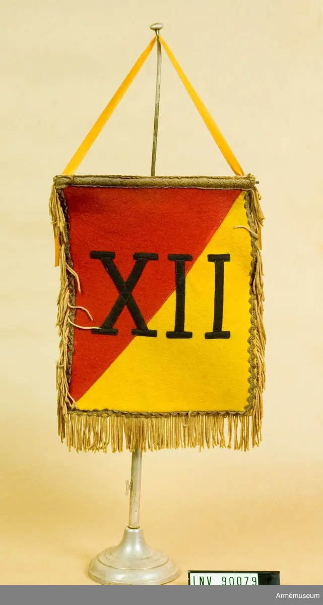 Kongolesiskt trofé. Tvärgående delad. En gul sida och en röd med romerska siffran XII i svart. Gyllene frans på alla sidor utom överst. 
