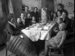 30-årskalas. Damer och barn runt ett dukat bord. På bordet e