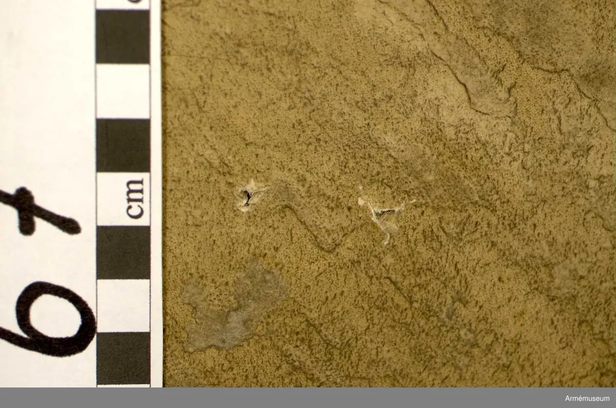 Kittel av koppar och skinn av kalv med fast spännring. Fot av järn fastnitad med kopparnit. Skruvar och skruvfästen av järn. Bärrem av kalvskinn i två lager med spänne av järn.