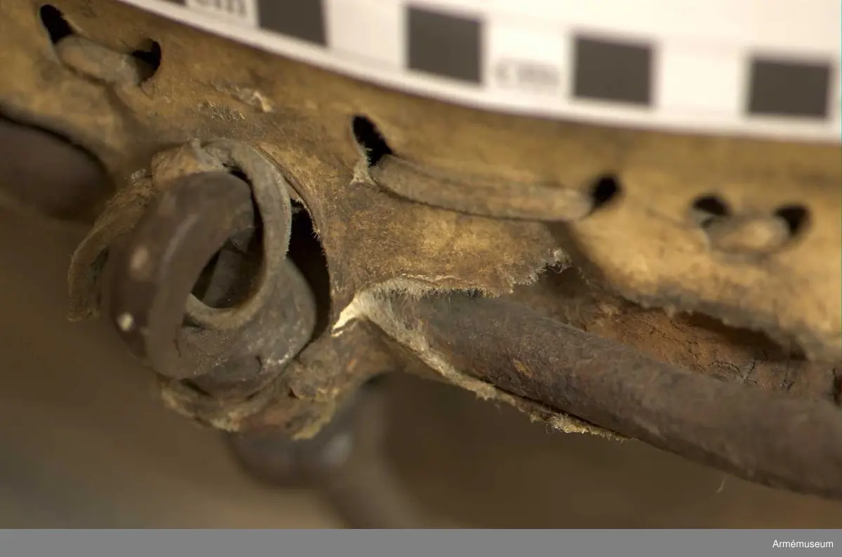 Kittel av koppar och skinn av kalv med fast spännring. Fot av järn fastnitad med kopparnit. Skruvar och skruvfästen av järn. Bärrem av kalvskinn i två lager med spänne av järn.