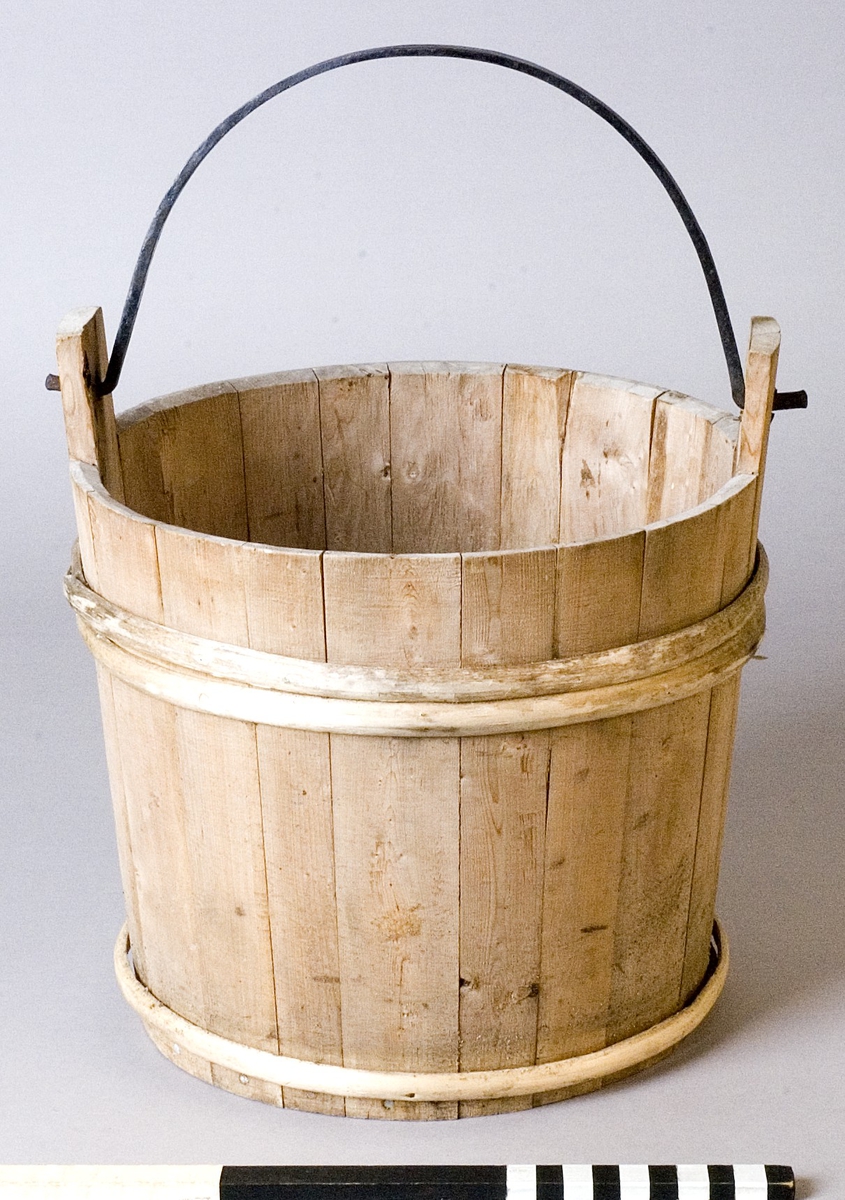 Spann av trä med smitt handtag av järn. Spannen utförd i laggteknik och hålls samman med två band av eneträ.