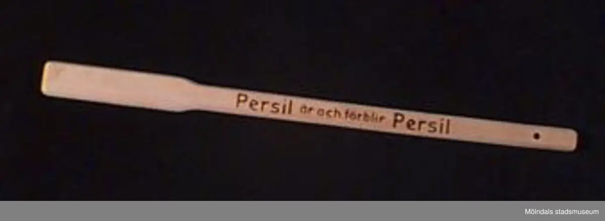Tvättkäpp i förpackning - båda märkta: "Persil är och förblir Persil" ( i svart tryck). Förpackningen trasig, käppen oanvänd. Märkt med tusch (?) på baksidan: "Hulda Olausson". Har tillhört givarens svärföräldrar som tvättade i Persil och lade i blöt i Henko. Utdelad i samband med reklamfilm på 1930-talet.Tvättkäppar användes för att trycka ned tvätten och röra om den i vattnet. Att den inte kom till användning berodde på att i bostadsområdet i Kålltorp där ägaren bodde så fanns det tvättutrustning i tvättstugan.