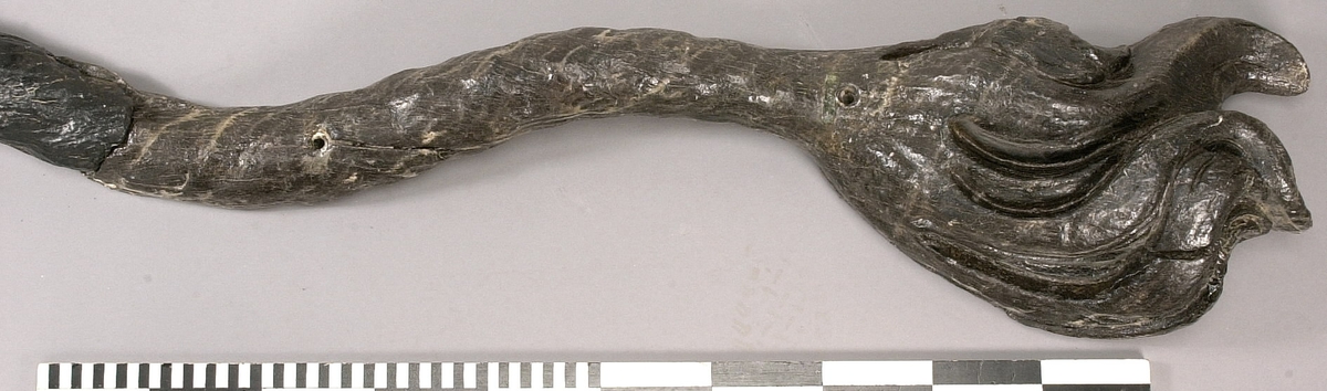 Skulpterad lejonsvans, lagad i rotändan. Svanstofsen är stor och yvig. Svansens baksida är slät.

Text in English: A sculpted lion''s tail, broken off where it was attached to the lion''s hind quarters. The tuft is large and bushy. The reverse side is smooth.