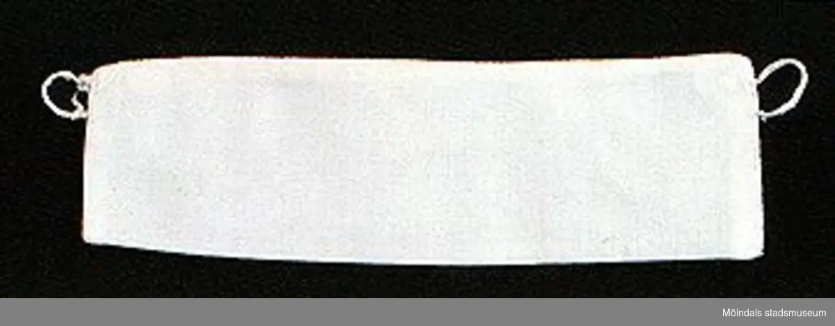 12 par vita lösmanschetter använda tillsammans med långärmade plagg. En del märkta med nr 41. 02253_1 L: 160 mm B: 55 mm._2 L: 160 mm B: 45 mm._3 L: 170 mm B: 60mm. Ribbat tyg._4 L: 190 mm B: 55 mm. Ribbat tyg._5 L: 200 mm B: 50 mm. Hålsömsprydda._6 L: 165 mm B: 80 mm. Hålsömsprydda (ej stärkta, märkta 15)._7 L: 160 mm B: 80 mm. Hålsömsprydda._8 L: 200 mm B: 50 mm. Hålsömsprydda._9 L: 180 mm B: 50 mm. Öglemönstrad spets längs kanten._10 L: 170 mm B: 55 mm. Smal spets längs kanten._11 L: 160 mm B: 45 mm. Spets längs kanten._12 L: 165 mm B: 50 mm. Ögleartad spets längs kanten.Paren förvaras i en tom chokladask (Cloetta Bristol praliner). Dessa har använts av vårdarinna Karin Hasselberg på Stretered.